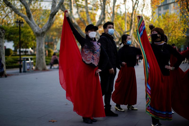 People wearing protective masks dance at a park