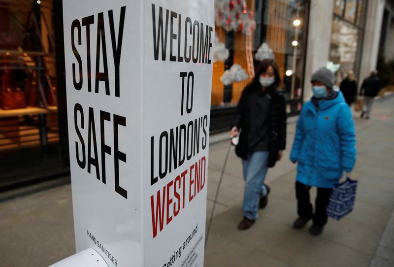 Shoppers walk past a Coronavirus related warning sign, in London