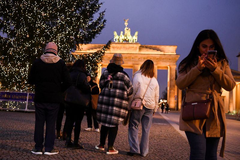 People pass by a Christmas tree close to Brandenburg gate