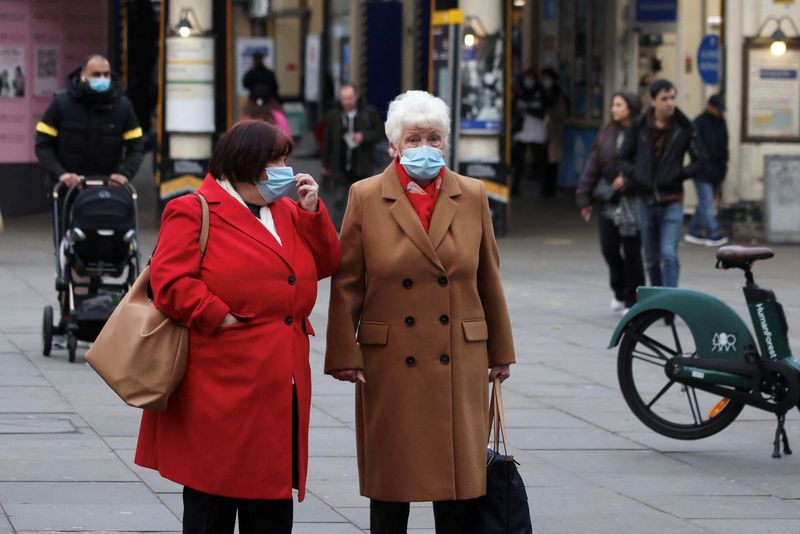 Women wearing face masks wait to cross a street in