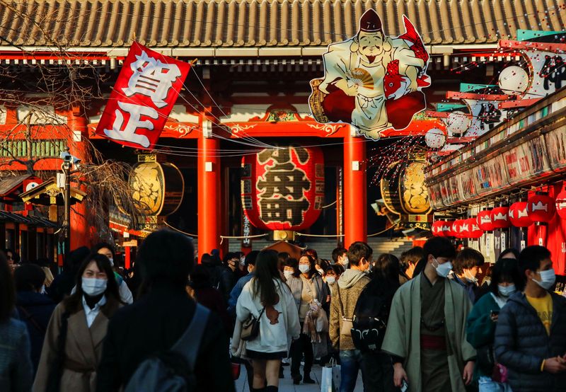 Visitors wearing protective face masks walk under decorations for the