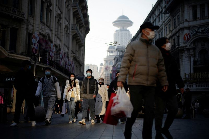 People wearing protective face masks walk on a street, following