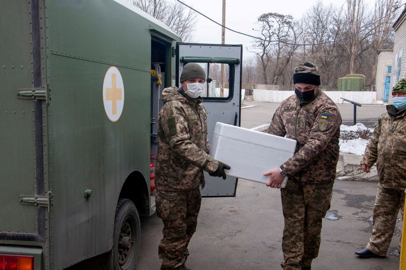 FILE PHOTO: Ukrainian servicemen carry a box with the Oxford-AstraZeneca