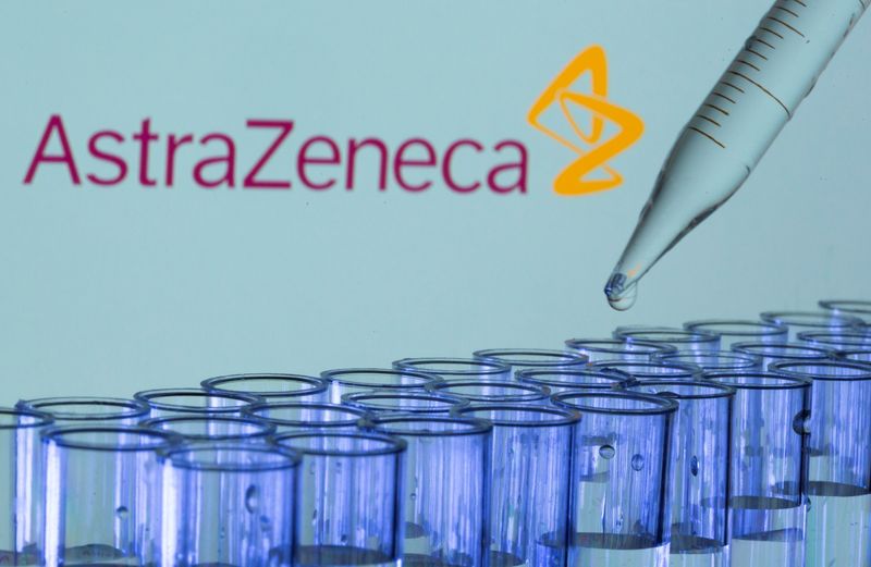 Test tubes are seen in front of a displayed AstraZeneca