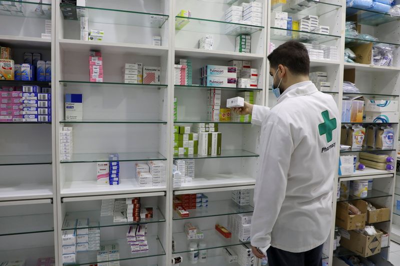 A pharmacy employee holds a box of medication in Beirut