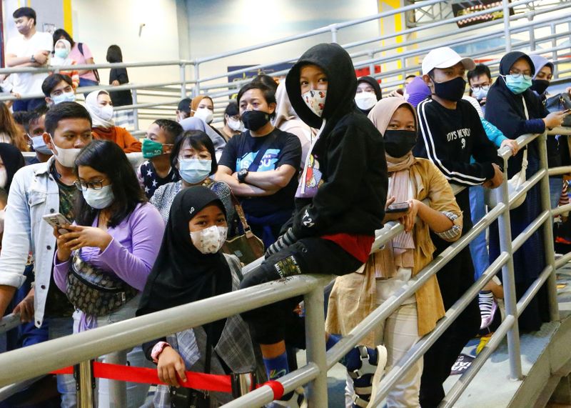 People wearing protective face masks wait for their turn to