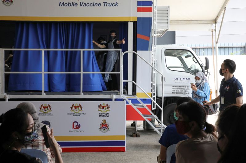 Medical worker gestures inside a COVID-19 vaccination truck in Kuala
