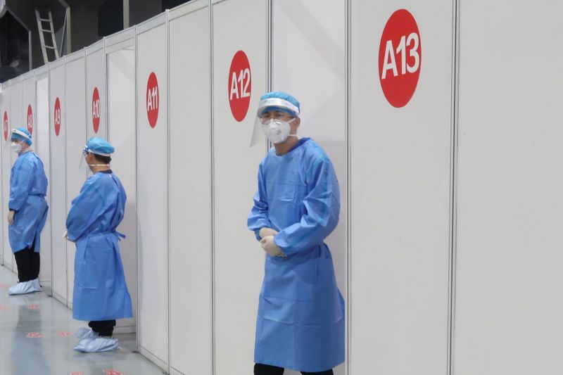 Staff members wait outside booths where people receive a vaccine