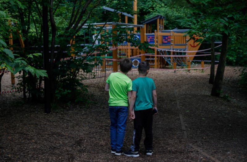 Boys look at a taped-off playground in a park in