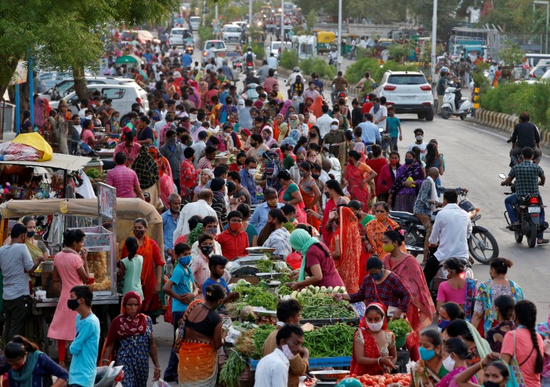 People shop at a crowded roadside vegetable market in Ahmedabad