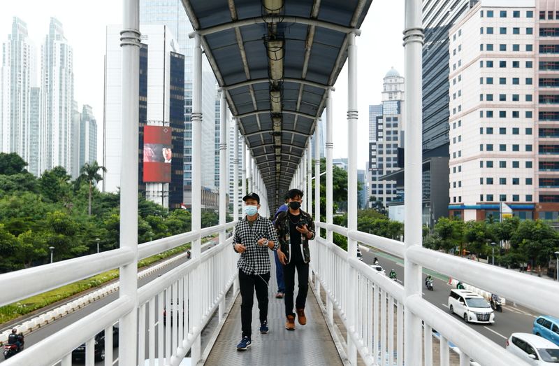 People wearing protective face masks walk on a bridge in