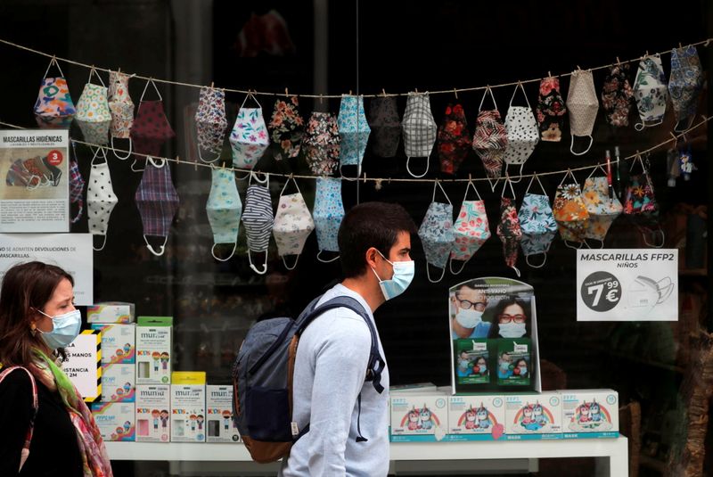 FILE PHOTO: People wear protective masks as they walk past