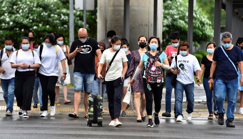 FILE PHOTO: People wearing face masks cross a road amid