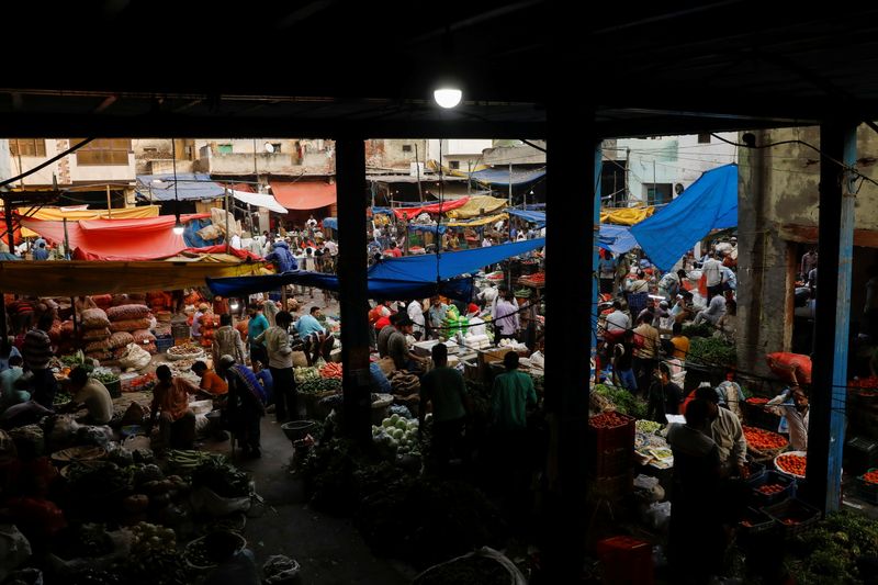 People shop at a crowded wholesale vegetable market after authorities
