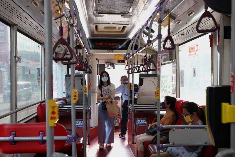 People wearing protective face masks get in a bus amid