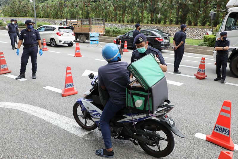 Police officers check vehicles at a road block during an