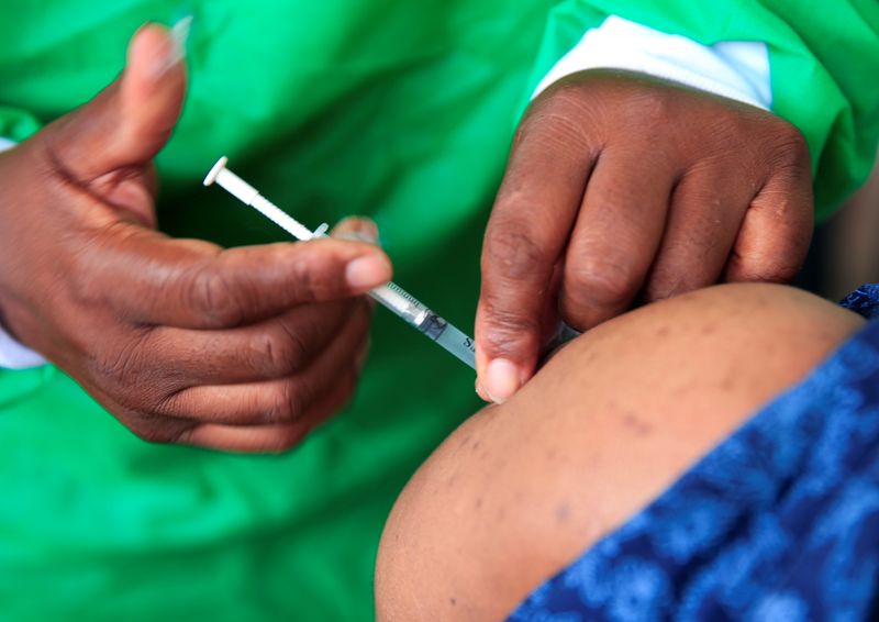 A nurse vaccinates a health worker against the coronavirus disease