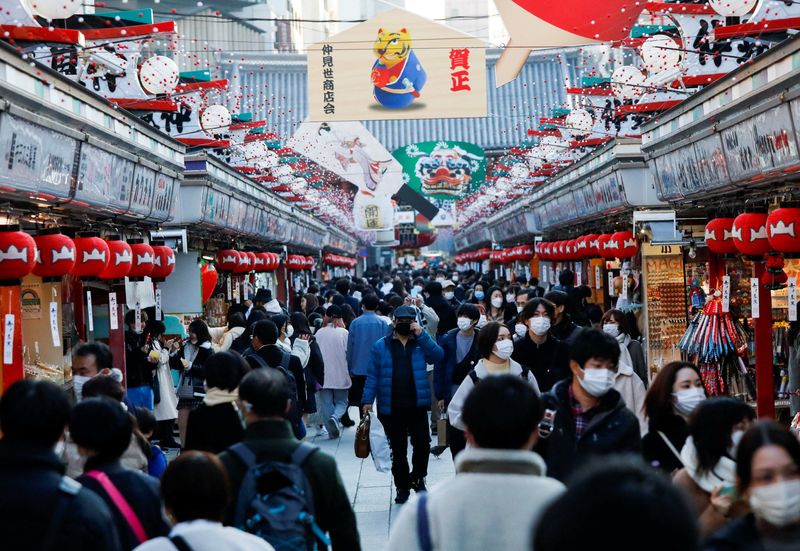 Visitors wearing protective face masks walk under decorations for the