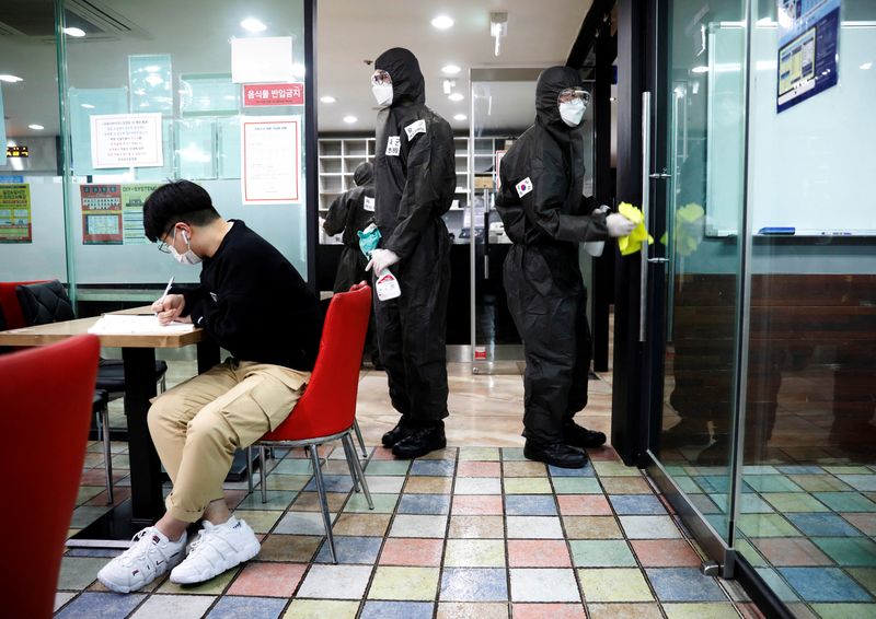 South Korean soldiers clean doors with disinfectant at a cram