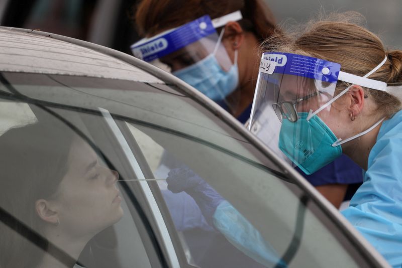 A medical worker administers a test at a drive-through COVID-19