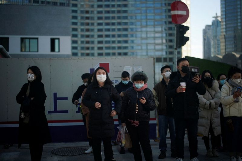 People wearing protective masks walk on a street, following new