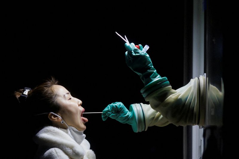 A woman receives a throat swab test at a street