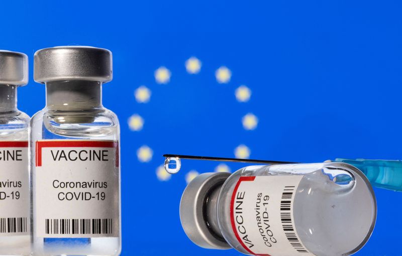 Illustration shows vials labelled “VACCINE Coronavirus COVID-19” and a syringe