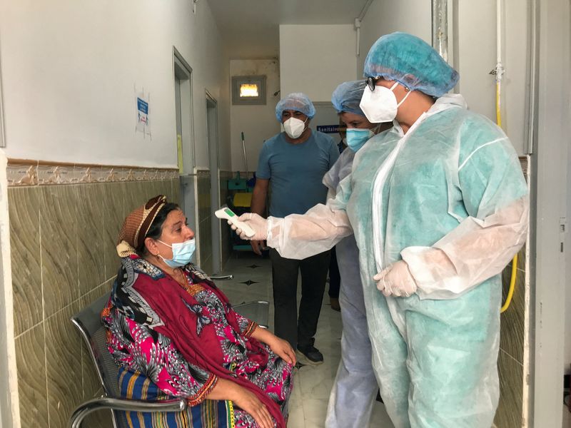 A medical worker checks a woman’s temperature in Ait Bouada