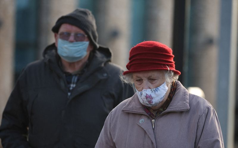 People wearing face masks walk through the town centre, amid