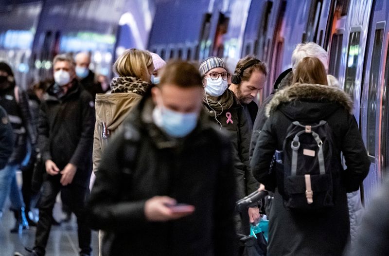 FILE PHOTO: Passengers wearing protective masks walk on a platform