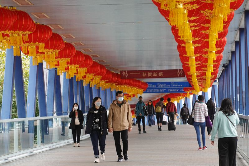 Pedestrians wearing face masks walk on a footbridge in Hong
