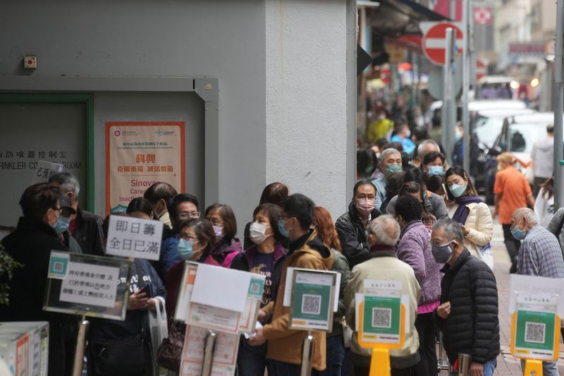 People wearing face masks queue outside a community vaccination centre