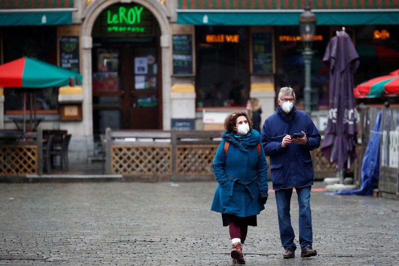 FILE PHOTO: People wearing protective face masks walk on a