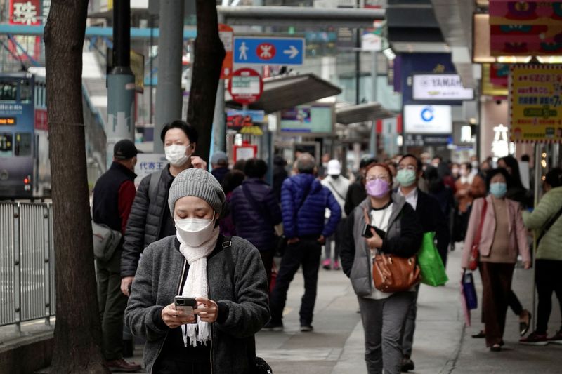 Pedestrians wearing face masks walk on a street in Hong