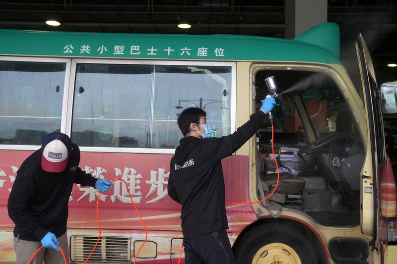FILE PHOTO: Cleaning staff spray disinfectant on a public minibus