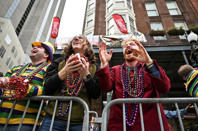 Spectators reach to catch Mardi Gras beads during Carnival celebrations