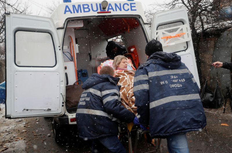 Medical specialists transport an injured woman to an ambulance following