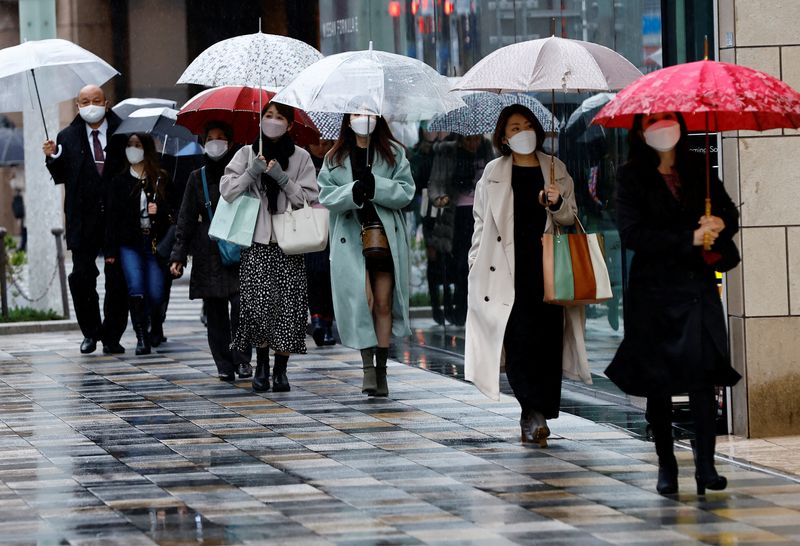 Pedestrians wearing protective face masks walk at a shopping district