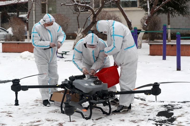 Workers prepare a drone to disinfect a residential compound under