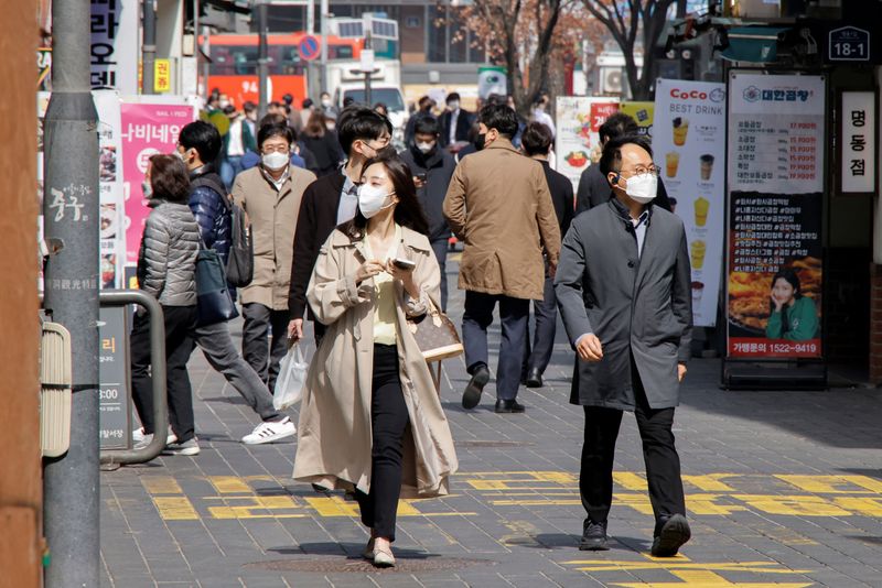 People wearing masks walk in a shopping district amid the