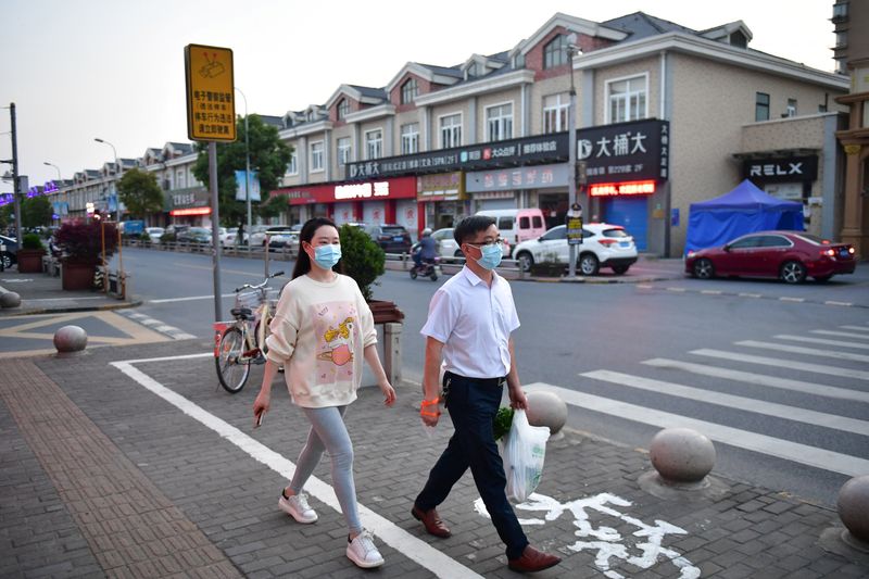 Residents walk on a street as Shanghai eases lockdown in