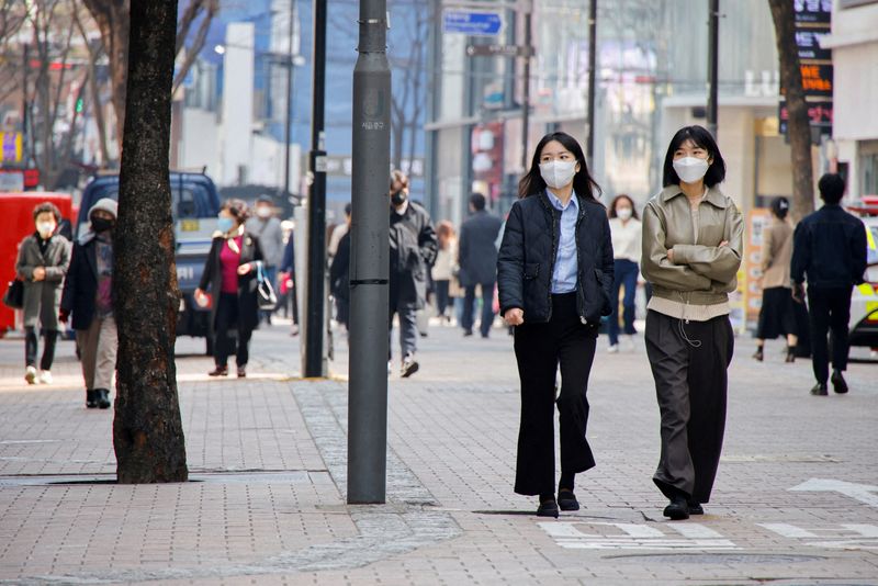 FILE PHOTO: Women wearing masks walk in a shopping district