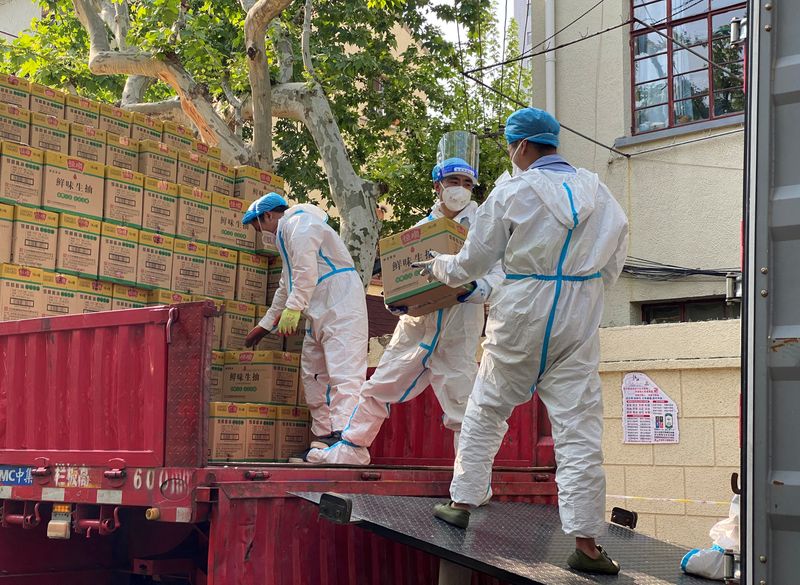 People in protective suits unload boxes labeled soy sauce from