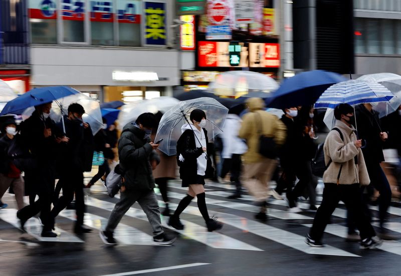 FILE PHOTO: Pedestrians wearing protective face masks walk at a