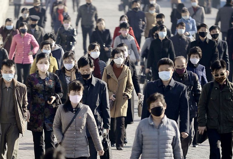 FILE PHOTO: People wearing protective face masks commute amid concerns