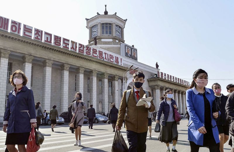 FILE PHOTO: People wearing protective face masks walk amid concerns