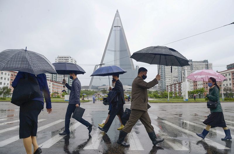 FILE PHOTO: People wearing protective face masks walk amid concerns
