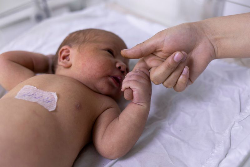 FILE PHOTO: A newborn baby holds on a nurse’s finger