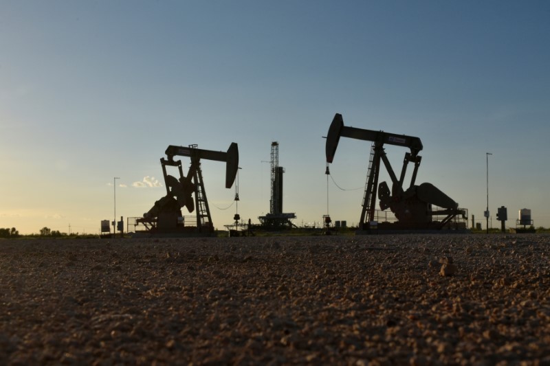 FILE PHOTO: Pump jacks operate in front of a drilling