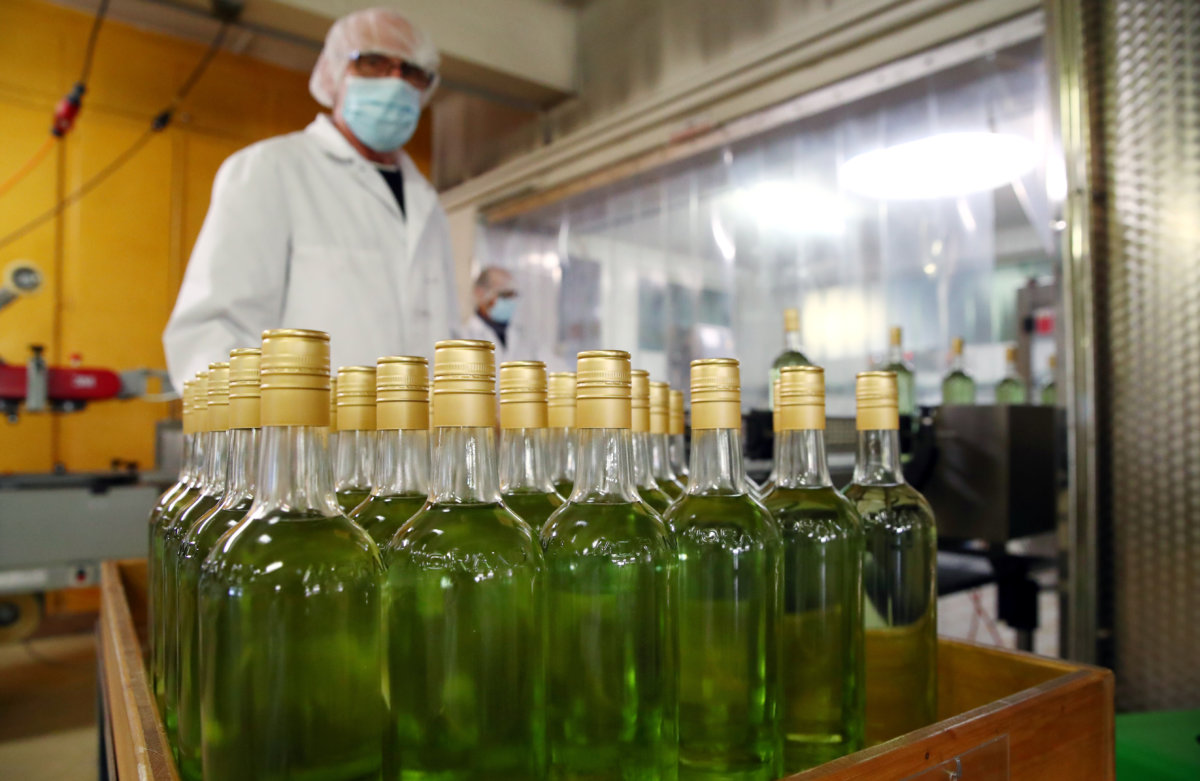 Staff lines a bottle into a labeller at Swiss distiller